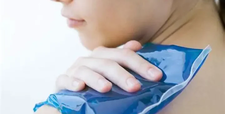 Donna applica ghiaccio sulla spalla dolorante per ridurre l'infiammazione causata dalla spalla congelata